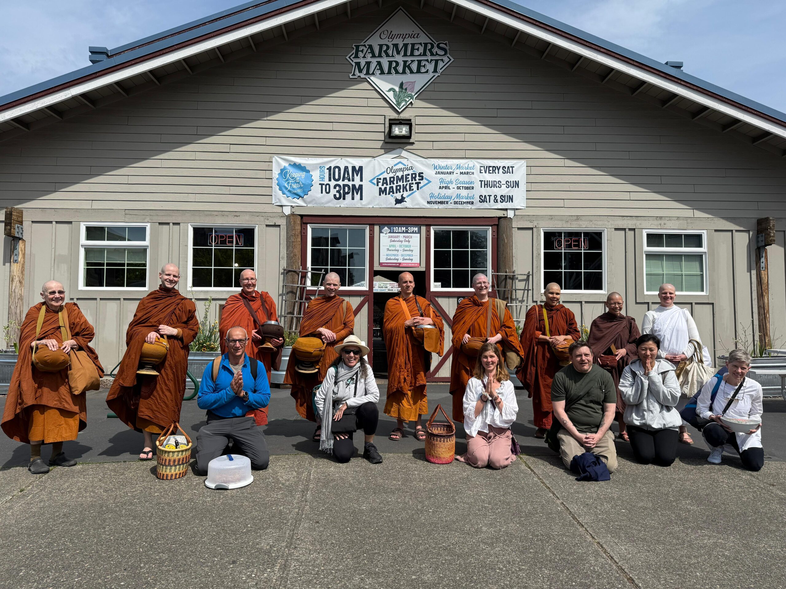 2026-05-01 At Farmers Market on Almsround monastics and lay people group photo in front of the Farmer's Market